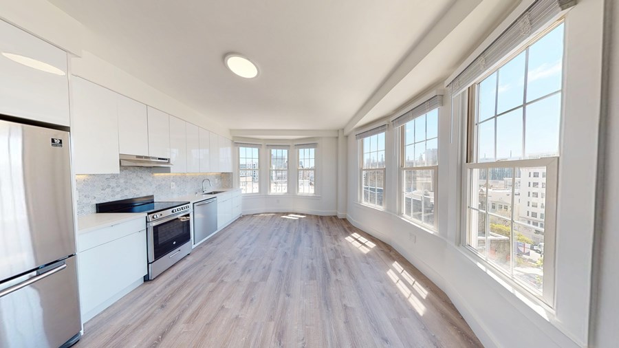 A spacious kitchen with white cabinets and a stainless steel refrigerator.
